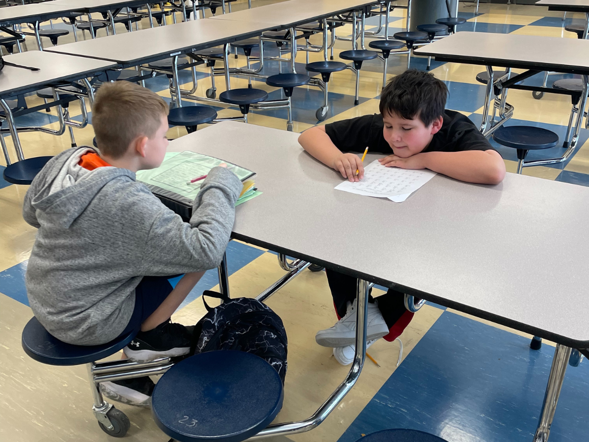 Two boys sitting at a table working on homework.